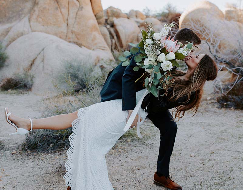 Verliebtes Brautpaar mit Brautstrauß in inniger Umarmung – romantischer Hochzeitsmoment